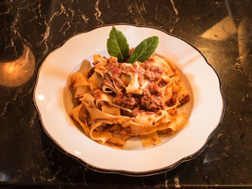 Flat Spaghetti noodles with meat sauce and topped with cheese and basil