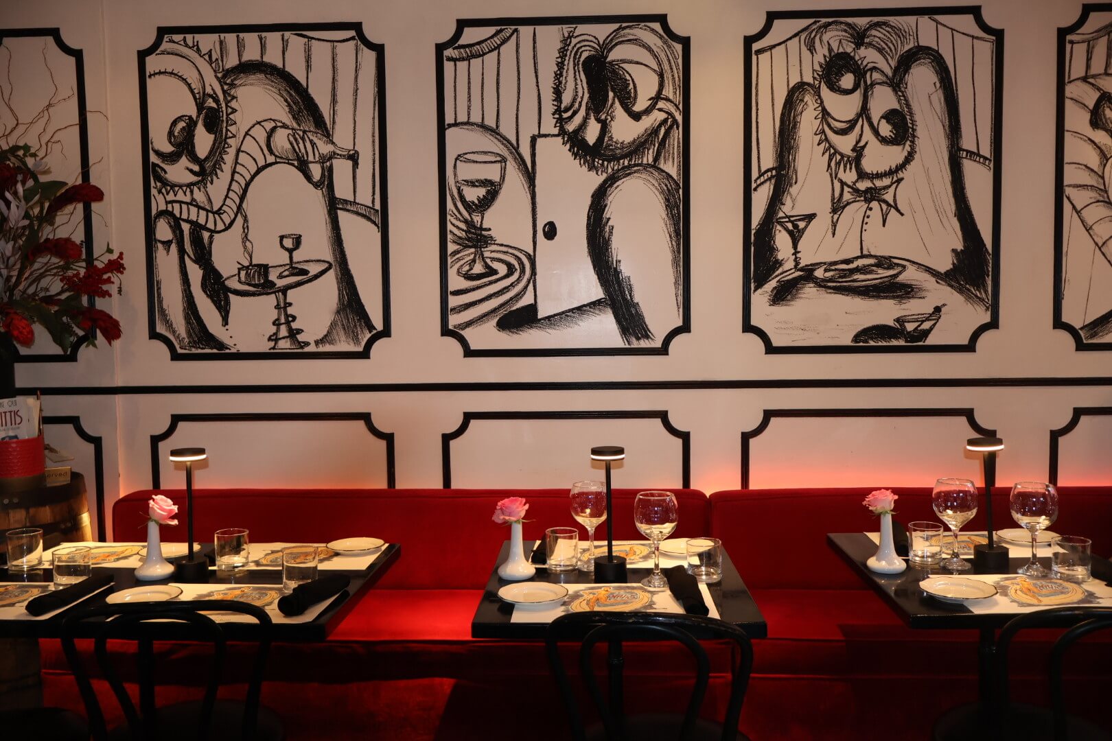 Red booths with two black tables, two black chairs, and a plant to the left