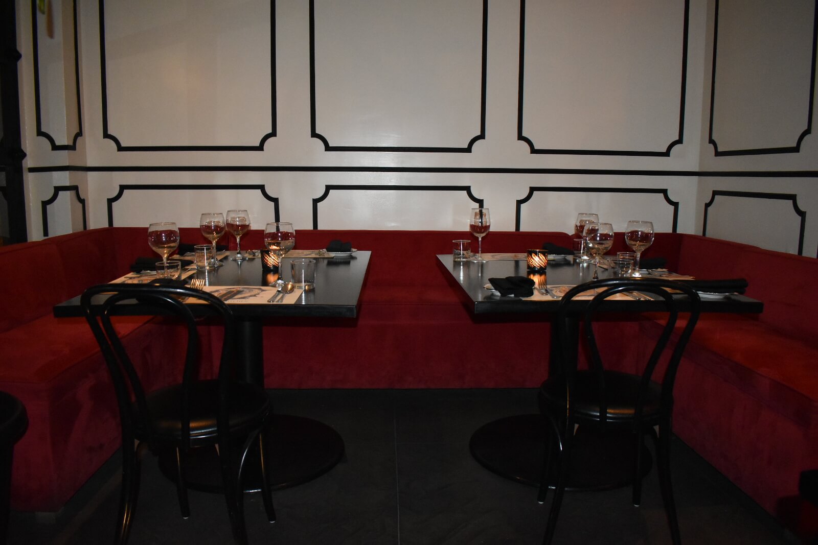 Red booths with two black tables and two black chairs